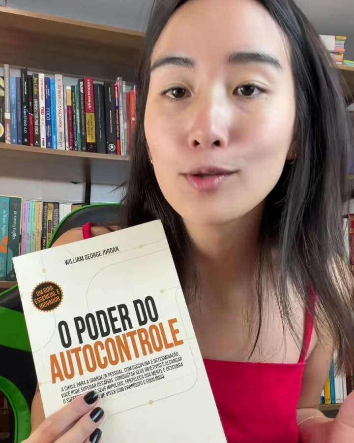 Leitora segurando a edição física diante da estante